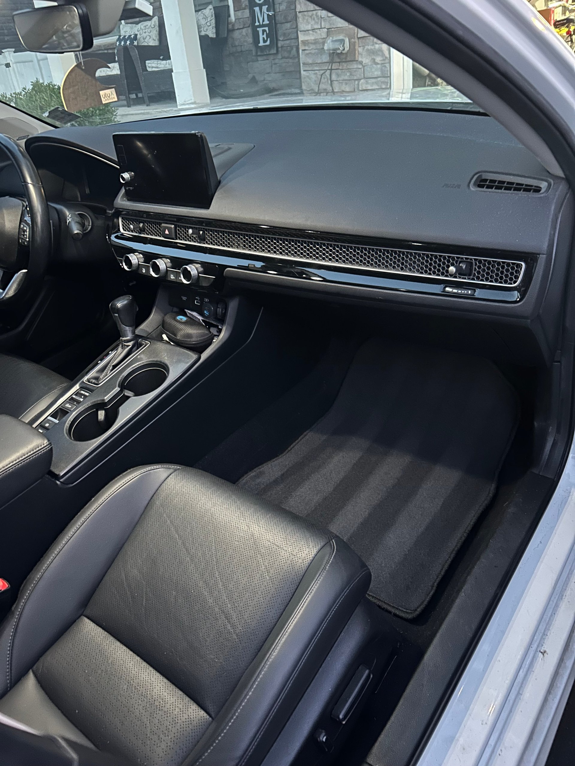 Interior view of a modern car dashboard and steering wheel with digital display and black leather seats