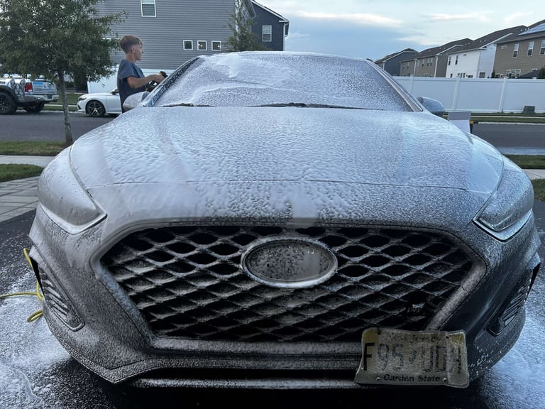 Blue sedan car covered in ice and frost in a residential driveway
