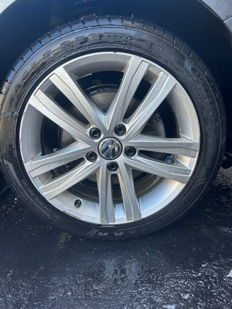 Close-up of a silver alloy wheel with black tire on dark asphalt pavement