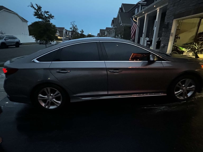 Gray sedan parked in driveway of suburban home during daytime